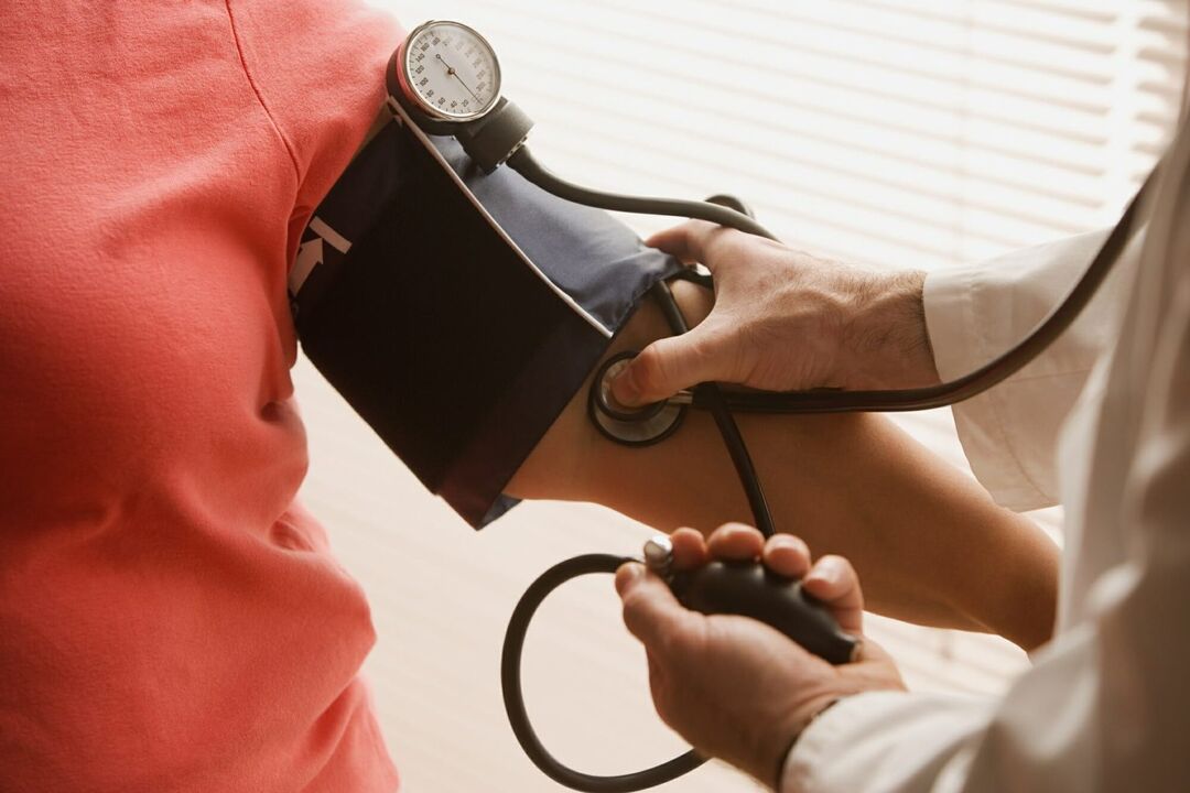 Lékař měření krevního tlaku pacienta s hypertenzí