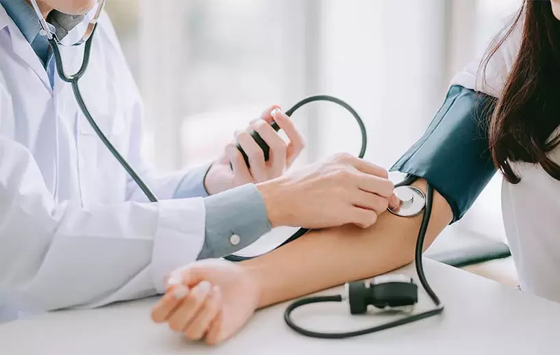 Kardiolog měří pacientovi krevní tlak k diagnostice hypertenze. 